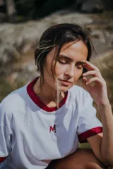 Remera blanca de algodón con cuello redondo y mangas cortas con puños de lurex rojo.