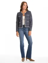 Chaqueta de tejido tweed en tono azul con sutiles destellos de lúrex. Presenta cuello a la base, abertura frontal y bolsillos decorativos. Las mangas largas incluyen detalle de botones metálicos dorados en los puños, y cuenta con vivos a contratono en los bordes.