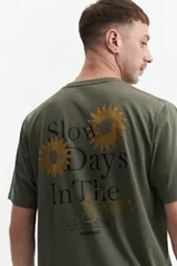 Remera verde militar de manga corta con estampado de soles y texto en la espalda.