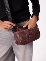 Bandolera Rusty modelo Velora, con estampado camuflado en tonos marrones y burdeos, cierre superior, bolsillo frontal y correa ajustable con logo impreso.