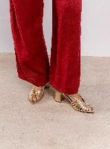 Sandalia dorada con tiras entrecruzadas, punta fina y pulsera regulable en el talón.