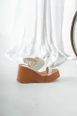 Sandalias de cuero color crema, con plataforma de madera color marrón.