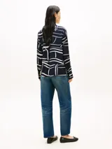 Camisa de Tommy Hilfiger de corte regular, confeccionada en sarga de viscosa azul marino con estampado abstracto de líneas blancas. Presenta cuello inglés, cierre frontal oculto con botones dorados, mangas largas con puños abotonados y detalle de plisado en la espalda.