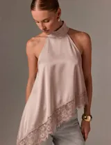 Blusa de satén rosada sin mangas, con cuello halter alto y dobladillo asimétrico decorado con encaje.