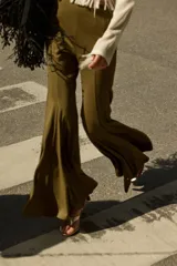 Pantalón acampanado color verde militar, de tiro alto, con costuras decorativas y nesgas en la rodilla que crean un efecto acampanado en los bajos.