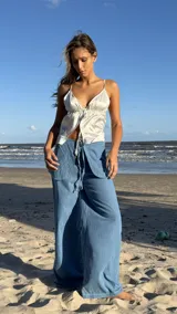 Top de satén color rojo vibrante, con escote pronunciado en V y lazos finos para atar en el frente y en la espalda. Presenta un diseño fruncido en la parte inferior.