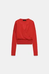 Chaqueta de punto color rojo con diseño de doble capa cruzada en el frente. Presenta cuello redondo, manga larga y cierre frontal con botones, con un acabado de tejido acanalado en el ruedo.