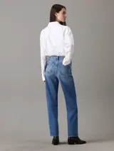 Camisa blanca de algodón Oxford, corte relaxed, cuello en punta, manga larga con puños abotonados y bajo redondeado.