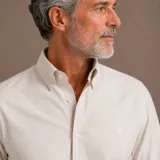 Camisa de manga larga confeccionada en algodón oxford, con cuello americano button-down y cierre frontal de botones. Presenta un diseño minimalista con un pequeño bordado en el pecho.