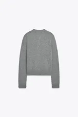 Chaqueta de tejido de punto color verde musgo, de corte cropped, con cuello redondo y cierre frontal de botones oscuros.