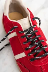 Zapatillas rojas de gamuza con detalles en cuero blanco y suela de goma color caramelo.
