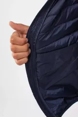 Campera gris acolchada con capucha, cierre frontal y bolsillos laterales con cierre.