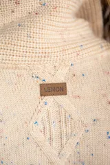 Cardigan beige con diseño de rombos en relieve, cuello con solapa y cierre frontal con botones.