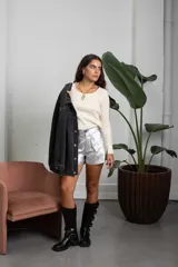 Campera de jean color negro lavado, de corte oversize, con detalle de tachas metálicas plateadas dispuestas en líneas verticales a lo largo de la prenda, cuello clásico, cierre frontal con botones metálicos y bolsillos en el pecho.
