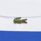 Remera polo Lacoste de manga corta con diseño de rayas horizontales blancas y azules, cuello camisero con cierre de dos botones y detalle de estampado gráfico en el pecho.