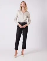 Pantalon de corte cigarette en color beige, confeccionado en tejido con apariencia denim y acabado satinado. Presenta tiro medio-alto, largo tobillero, cintura con presillas, cierre con gancho sastrero oculto, bolsillos laterales diagonales con botones forrados y pinzas traseras para un ajuste entallado.