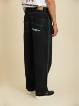 Jean de corte baggy fit, color negro, con costuras en contraste color verde y franjas laterales verdes.