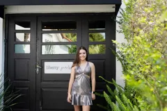 Vestido corto negro con lentejuelas, escote pronunciado en V con argolla central, cut-outs laterales bajo el busto y falda con volado.