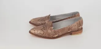 Mocasines de cuero plateado con acabado texturado, diseño clásico con costuras visibles y vira de suela natural cosida. Cuenta con taco plano de 2 cm y plantilla anatómica.
