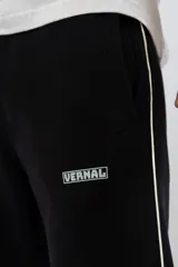 Pantalón de jogging negro con una franja vertical blanca a los costados y logo de la marca en la pierna izquierda.