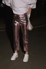 Pantalón de ecocuero con acabado metalizado en color rosado, de corte capri semi oxford y tiro medio-alto. Presenta cierre frontal con botón metálico y bolsillos traseros.