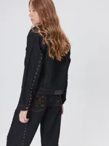 Campera denim crop de mezclilla oscura, con apliques metálicos en el pecho, bolsillos delanteros cruzados con detalles bordados y de parches.