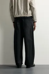 Pantalón relaxed fit negro confeccionado en tejido de algodón con estructura diagonal, estilo de cinco bolsillos y cierre frontal con cremallera y botón metálico.