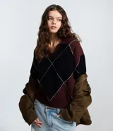 Buzo de tricot con cuello polo y diseño de patrón a cuadros en tonos bordó y negro. Presenta mangas largas y un calce amplio y relajado.