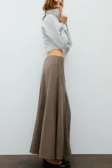 Falda larga de tiro alto, color negro, con diseño fluido y cintura elástica. Cierre lateral con cremallera oculta en costura.
