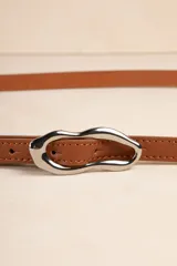 Cinturón fino color rojo de símil cuero con hebilla metálica irregular plateada.