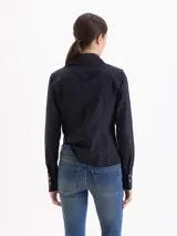 Camisa entallada de poplín color negro, con cuello clásico, cierre frontal de botones, mangas largas con puños anchos y bolsillos frontales con tapa.