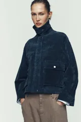 Cazadora estilo bomber confeccionada en piel, con cuello solapa, manga larga y cierre frontal con cremallera oculta y botones a presión. Presenta bolsillos delanteros de plastrón con solapa y botón a presión.