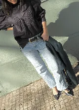 Blusa de lino color salmón con cuello alto, mangas abullonadas y detalle de alforzas en el frente. Presenta terminaciones con puntilla ondulada negra y cierre posterior con botones a la vista.