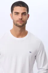 Remera T-shirt básica de algodón de manga larga, color blanco, con escote a la base y logo bordado en azul en el frente. De calce cómodo.