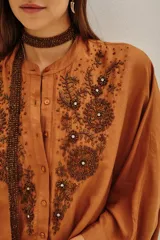 Camisa de viscosa color crema, con cuello mao y cierre frontal de botones. Presenta un delicado bordado floral en el frente y mangas tres cuartos con puños rectos.