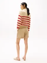 Sweater de punto color crema con rayas horizontales rojas, cuello alto con cremallera metálica y logo de Tommy Hilfiger bordado en el pecho.