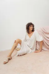 Vestido midi color blanco crudo, con escote en V, fruncido en el pecho y mangas cortas abullonadas.