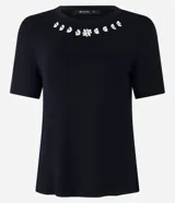 Blusa blanca de mangas cortas confeccionada en viscosa con cuello redondo con brillos en formas florales.