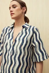 Vestido corto con estampado de líneas onduladas en blanco, negro y beige. Tiene cuello tipo solapa, escote en V y mangas 3/4.