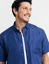 Camisa de manga corta azul con pequeños lunares blancos, cuello abotonado y bolsillo en el pecho.