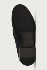 Mocasín de vestir para hombre, fabricado en piel con acabado en serraje de color azul marino. Presenta un diseño clásico con detalle de antifaz en el empeine, horma redonda, costuras visibles en el contorno y una suela sutil con ligero tacón.