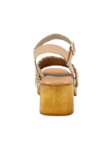 Sandalia de estilo sueco con plataforma y taco cuadrado de madera. Presenta una banda frontal tejida en rafia multicolor con detalles de tachas metálicas y una tira de sujeción al tobillo en cuero color nude con cierre de hebilla.
