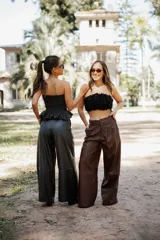 Pantalón de tiro alto confeccionado en cuero sintético, de corte amplio y pierna ancha con costura horizontal a media altura.