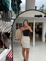 Pollera corta de cuero sintético con diseño de paneles y bolsillos frontales grandes. Presenta un corte recto y tiro medio.