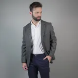 Saco de lana color gris con solapas de muesca, cierre de dos botones, bolsillo en el pecho y bolsillos delanteros con solapa.