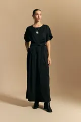 Pantalón ancho de tiro alto color marrón oscuro, con pinzas en la cintura, cinto incorporado y silueta fluida.