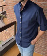 Camisa de lino color azul marino, de corte oversize, con cuello abotonado y botones en contraste. Presenta un pequeño logo bordado en el pecho.