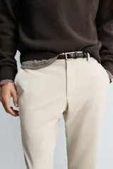 Pantalón de corte slim fit confeccionado en tejido elástico, con cintura elástica, cierre frontal con cremallera y botón, bolsillos laterales y bolsillos traseros de vivo.