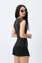 Remera sin mangas, ajustada al cuerpo, color gris oscuro o negro gastado, con cuello redondo y terminaciones de volados en las sisas. Estampado frontal con texto en blanco que dice "*rea ess*" y "*fearless*".