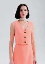 Chaleco corto color salmón con escote en V y tres botones frontales.